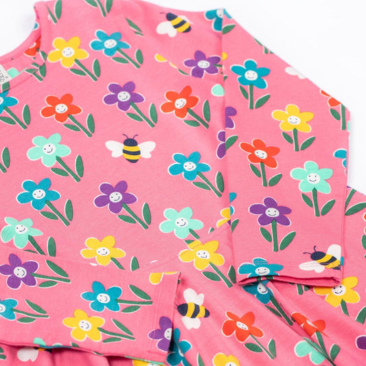 Pink dress with colorful floral and bee pattern on a white background