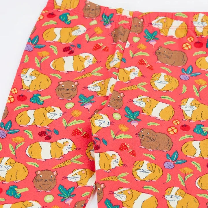 Pinkish-red children's leggings with a cartoon guinea pig and strawberry pattern, shown folded on a white background.