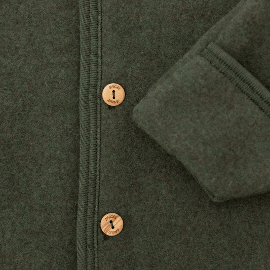 Close-up of a dark olive green wool jacket with a buttoned front and a folded cuff showing the ribbed lining.