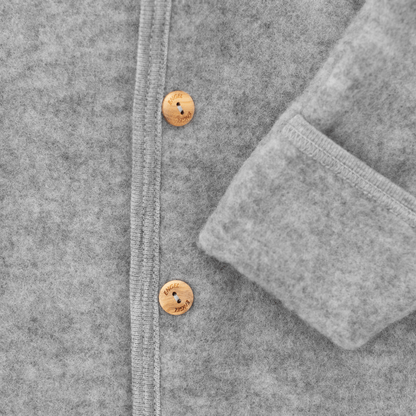 Close-up of a gray textured cardigan featuring a vertical button placket with two light brown wooden buttons and a folded cuff.