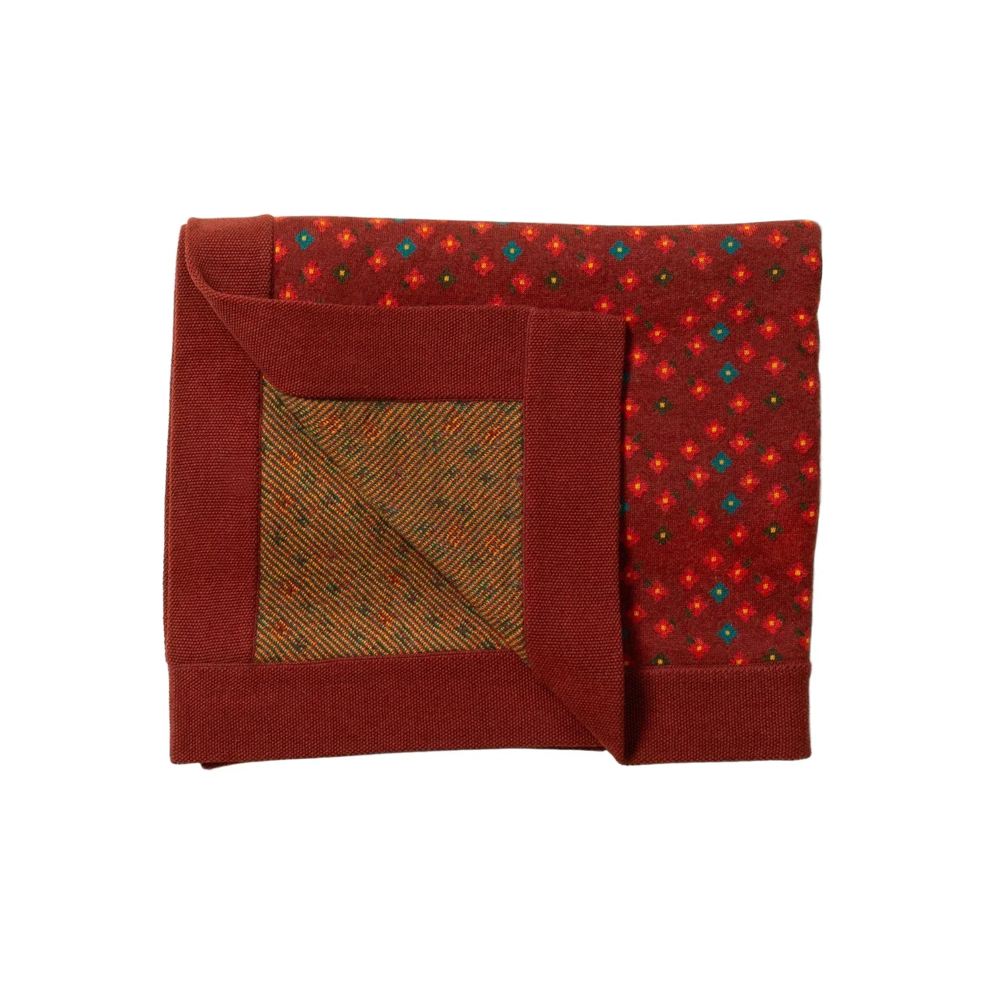 Folded red blanket with a patterned corner on a light background