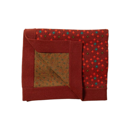 Folded red blanket with a patterned corner on a light background
