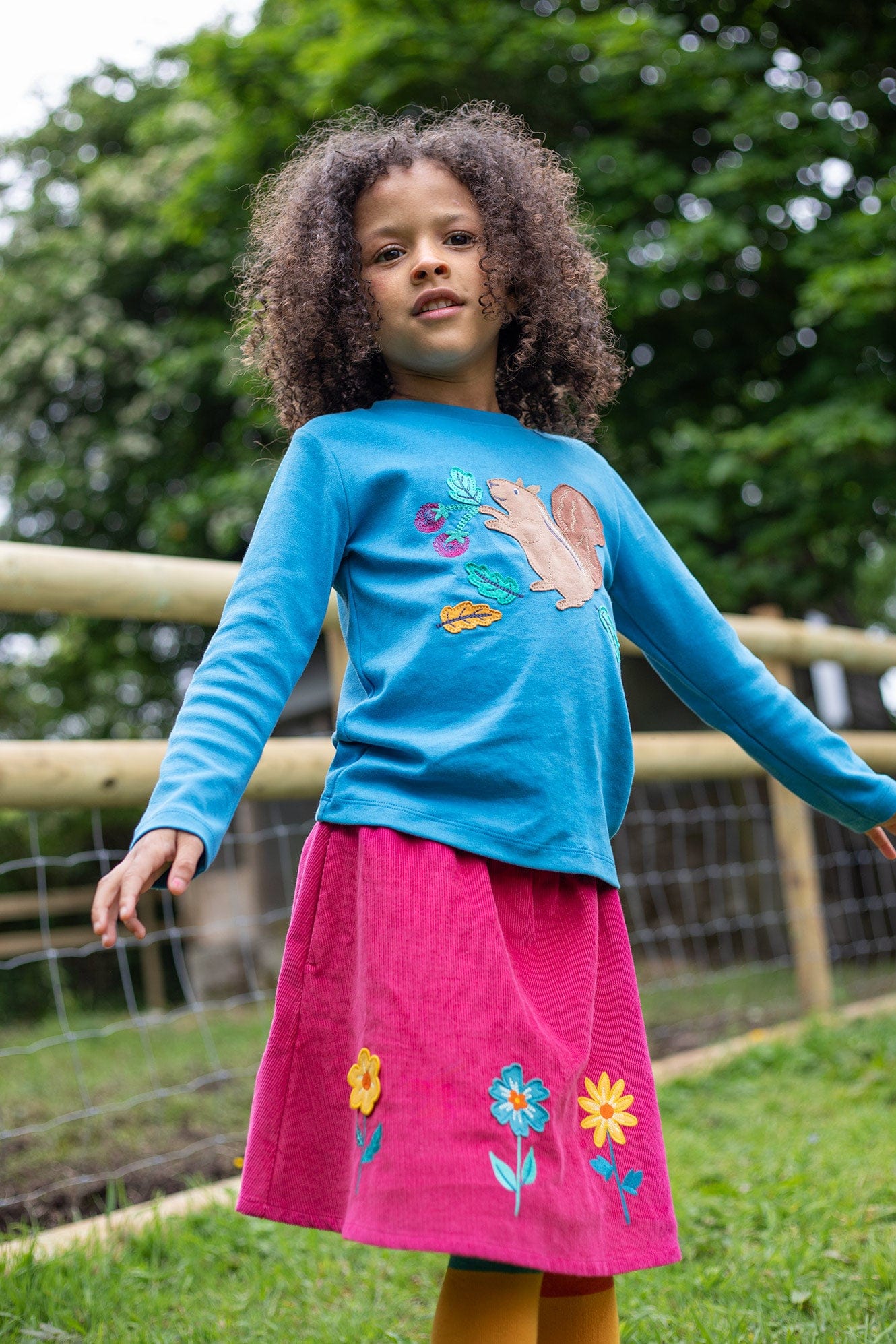 Long Sleeve Squirrel Top from Frugi worn with Katya Cord Skirt on girl outside in the green grass.