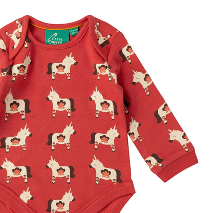 A red long-sleeve baby bodysuit with an all-over print of cowboy horses wearing red cowboy hats. The bodysuit has a green neck label that reads 'A Little Queen'.