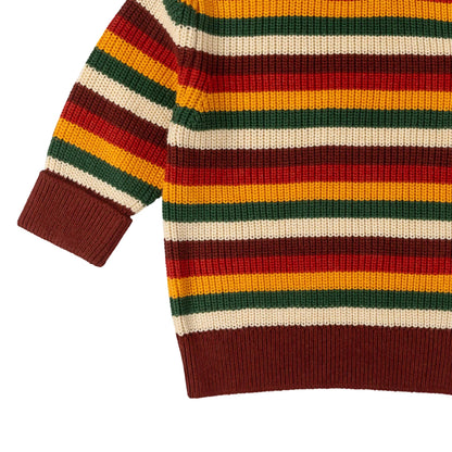 Colorful striped sweater with a mix of red, yellow, green, and brown on a light gray background