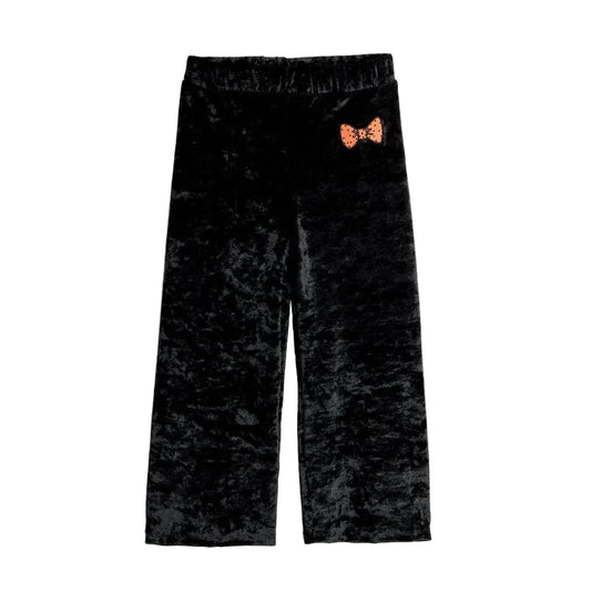 Black crushed velvet cropped pants with an elastic waistband and a small orange bow-tie graphic on the upper left hip, shown flat on a light gray background.